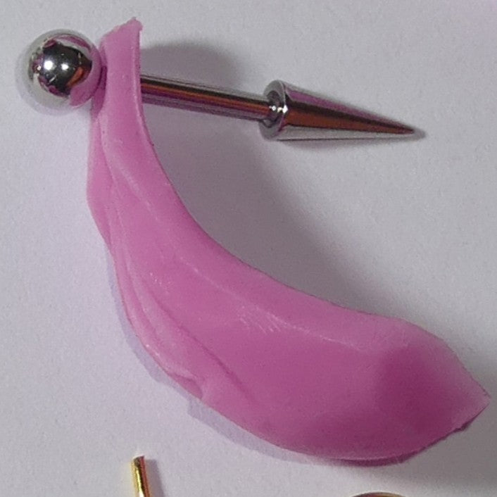 A pink silicone BarbieVagina accessory attached to a silver metal pin with a spherical end, photographed on a plain light background.