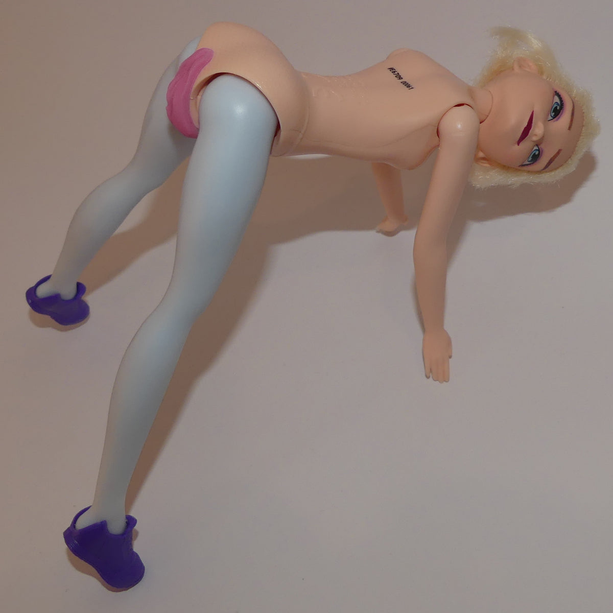 A blonde female action figure posed on all fours against a plain light background.