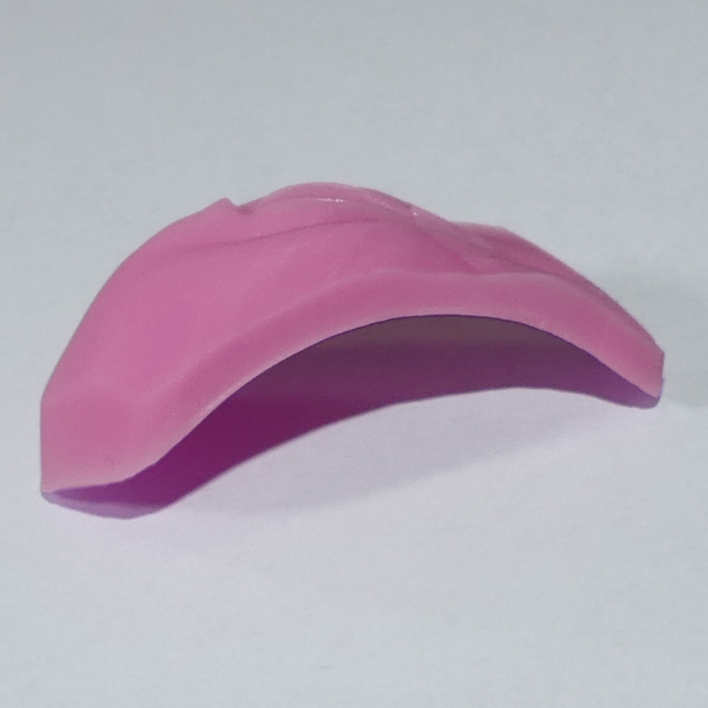 A pink curved silicone or rubber accessory, Barbie Vagina shown on a plain light gray background.