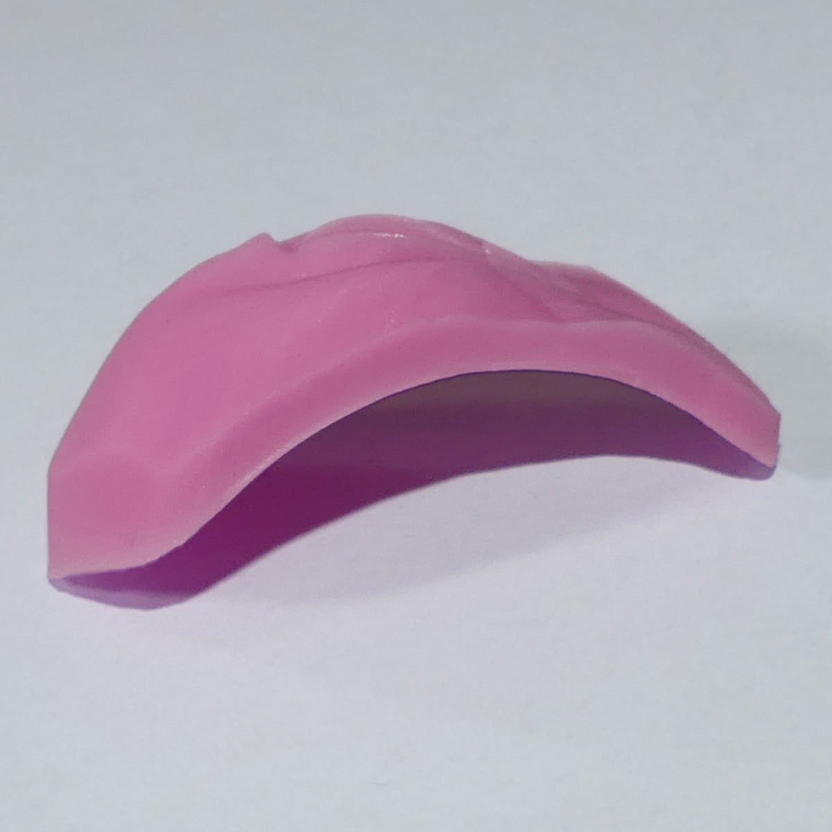 A pink curved silicone or rubber accessory, Barbie Vagina shown on a plain light gray background.