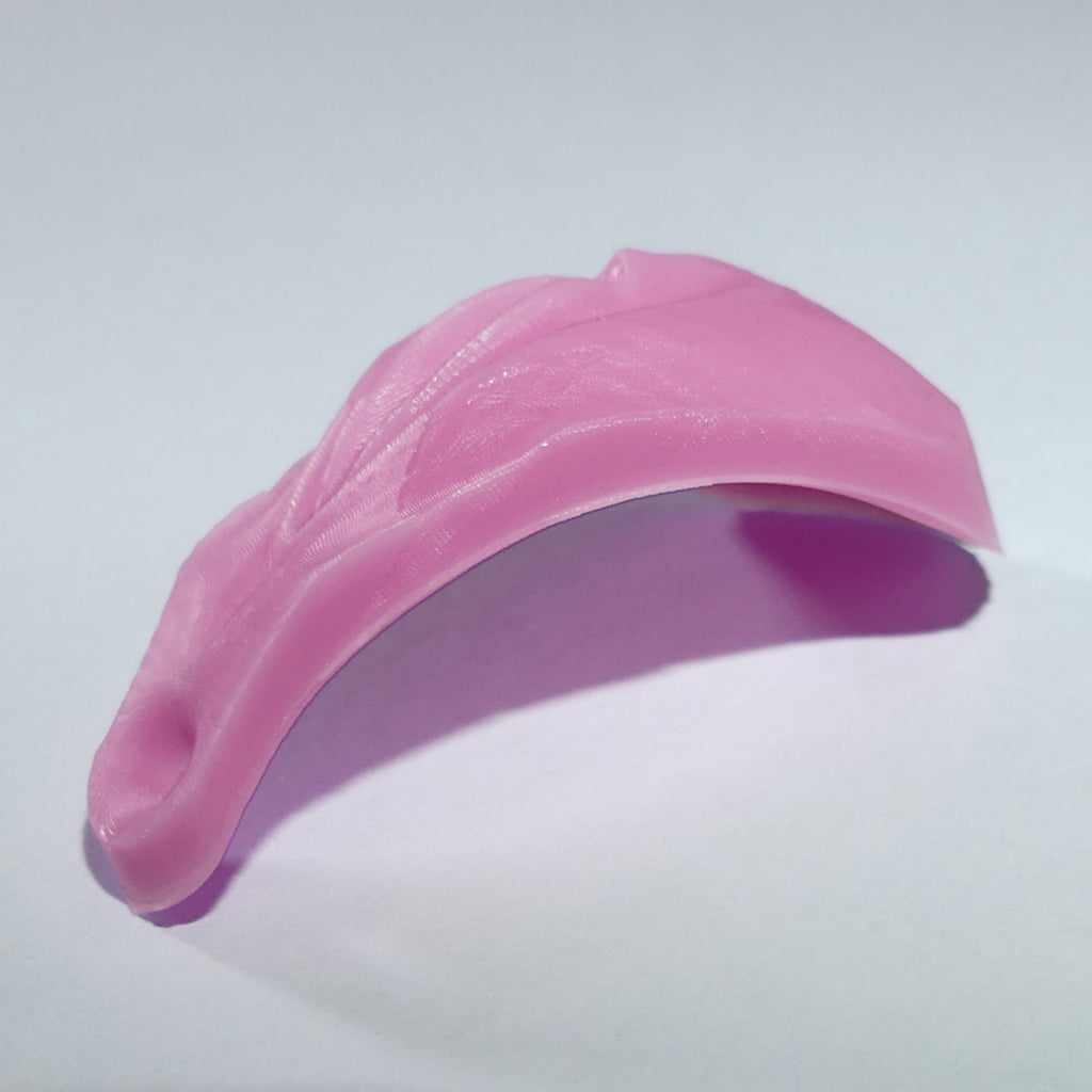 A pink vagina vulva curved silicone or rubber accessory with a textured surface and a small anal, shown on a plain light gray background.