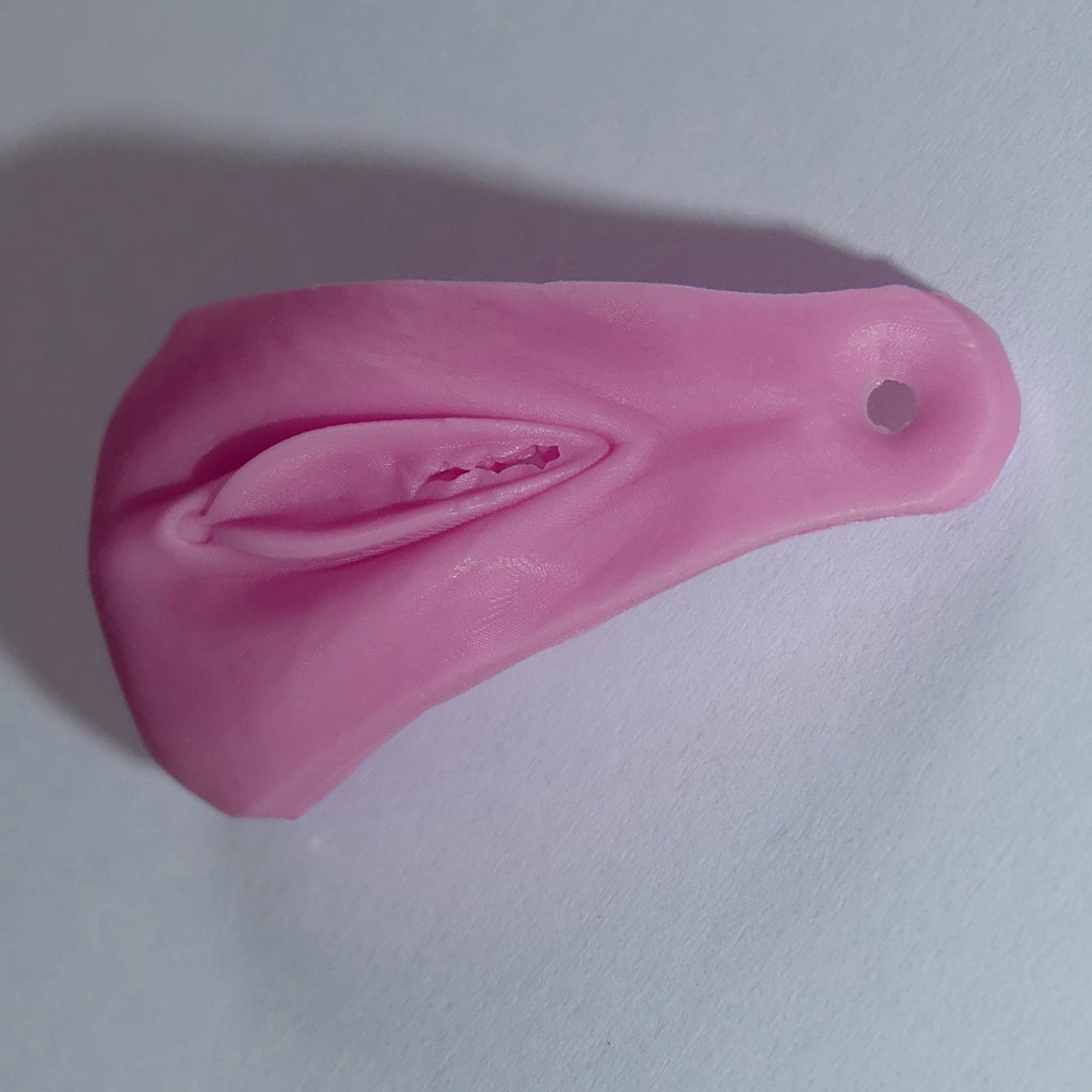 A pink silicone vagina adult novelty item with a textured interior and a small hole near one end, photographed on a plain light background.